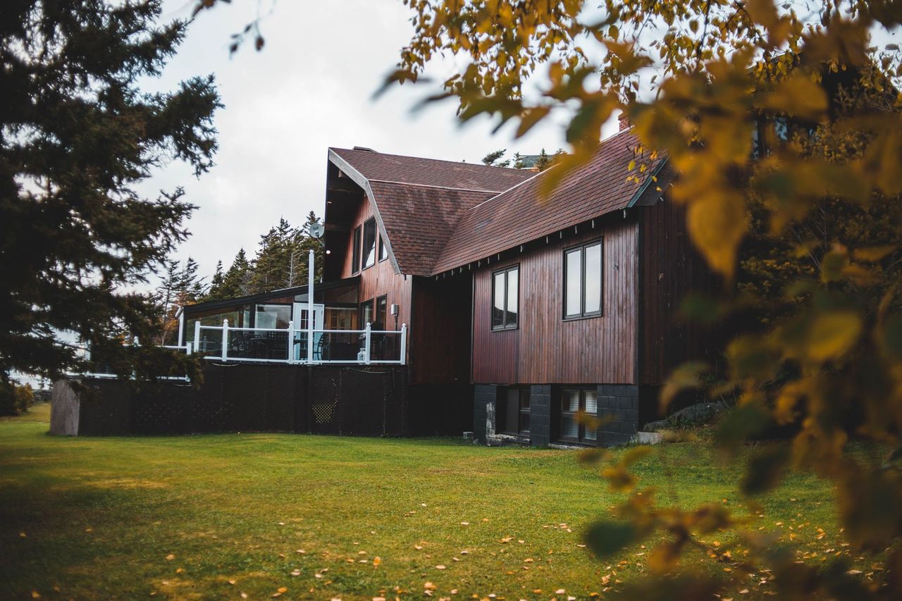 Casa de veraneo de madera con terraza y jardín, rodeada de bosque