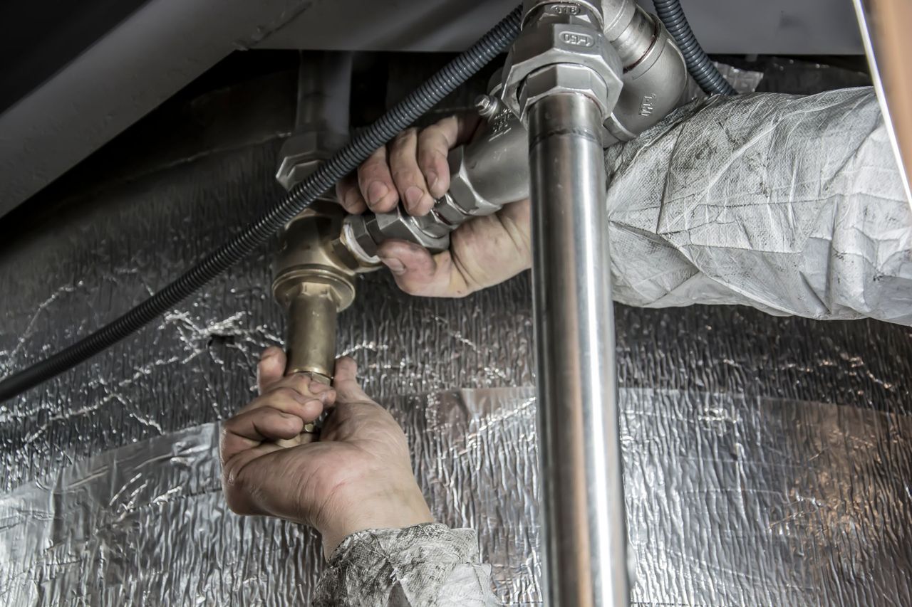 Gasfiter con guantes ajustando cañerías con llave